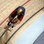 Image of a man on fixie at velodrome riding a brakeless track bike.