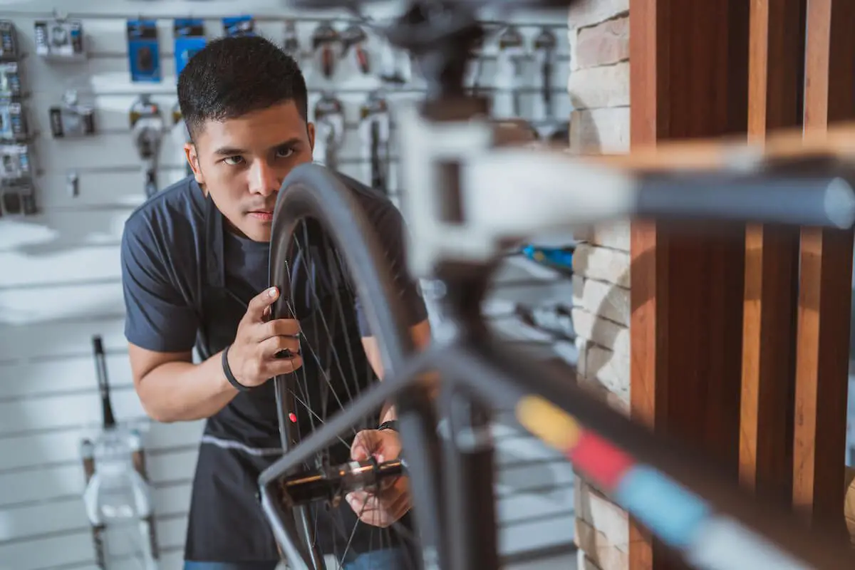 Image of a man with an apron repairing a bicycle in bike shop.