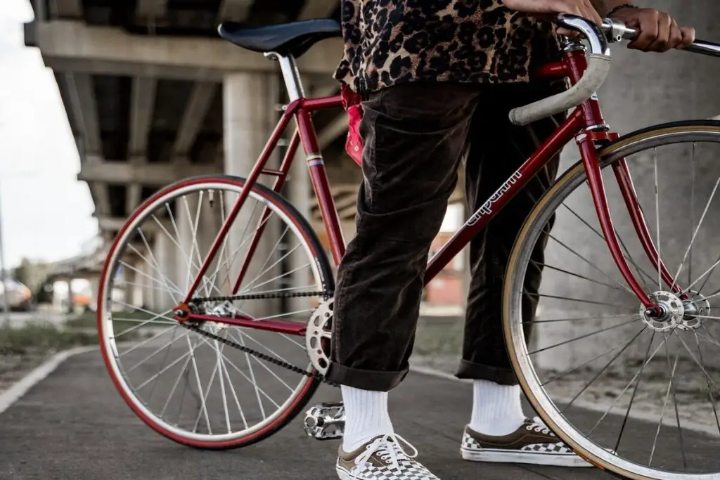 Image of a cyclist standing with a fixie bike under a bridge. Source: pexels