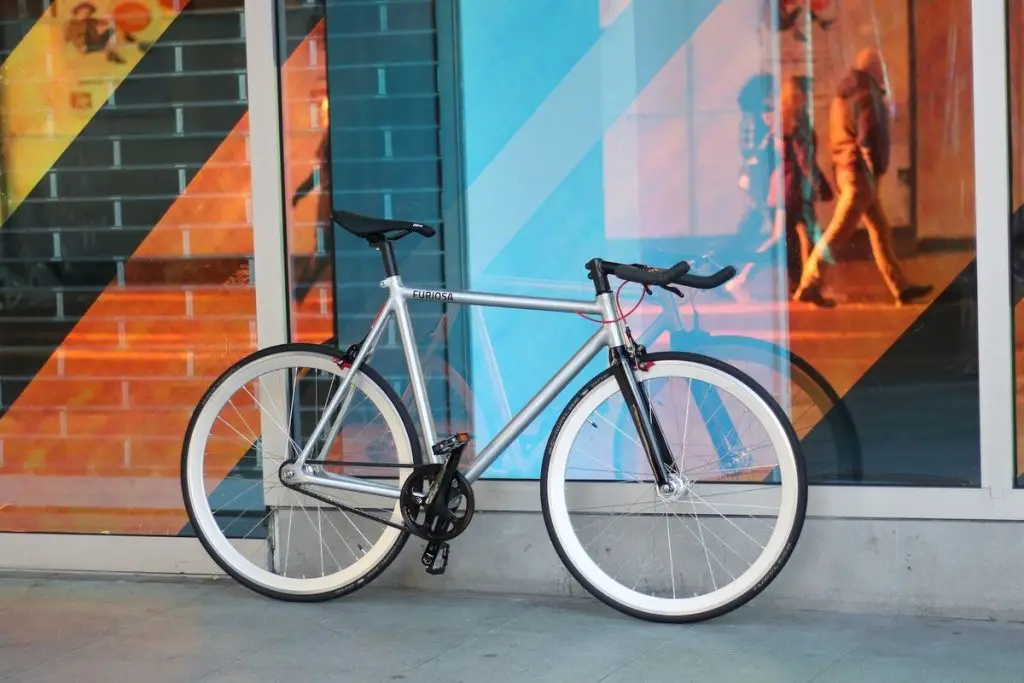 Image of a fixie bike on leaning on a glass wall. Source: Pexels