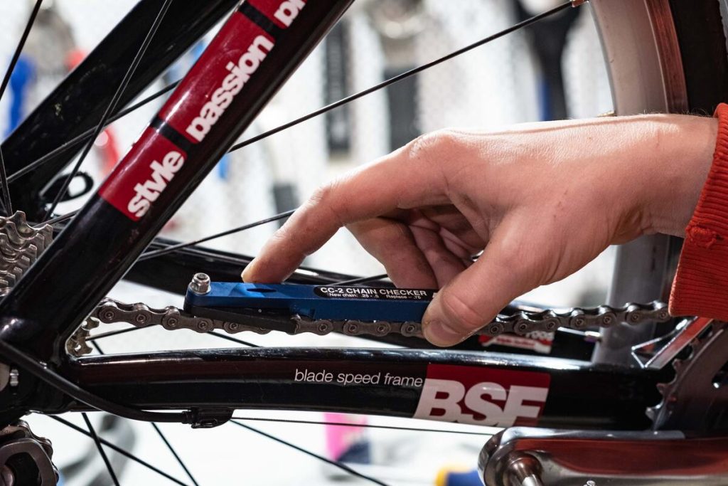 Image of a man using a chain checker on a bicycle wheel. Source: unsplash