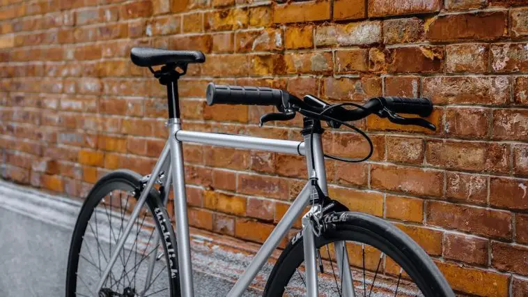 Gray fixed gear bike with thick-slick tires against brick background. Source: Zifeng Zhang, Unsplash