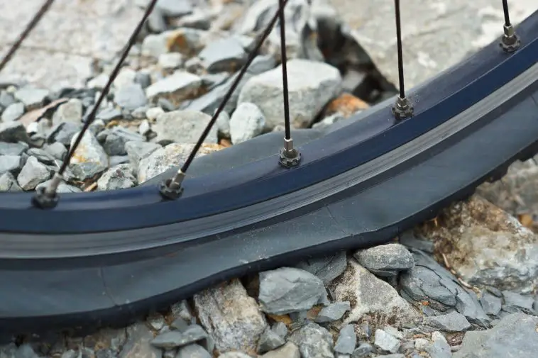 Black flat tire on gravel road. Source: Adobe Stock