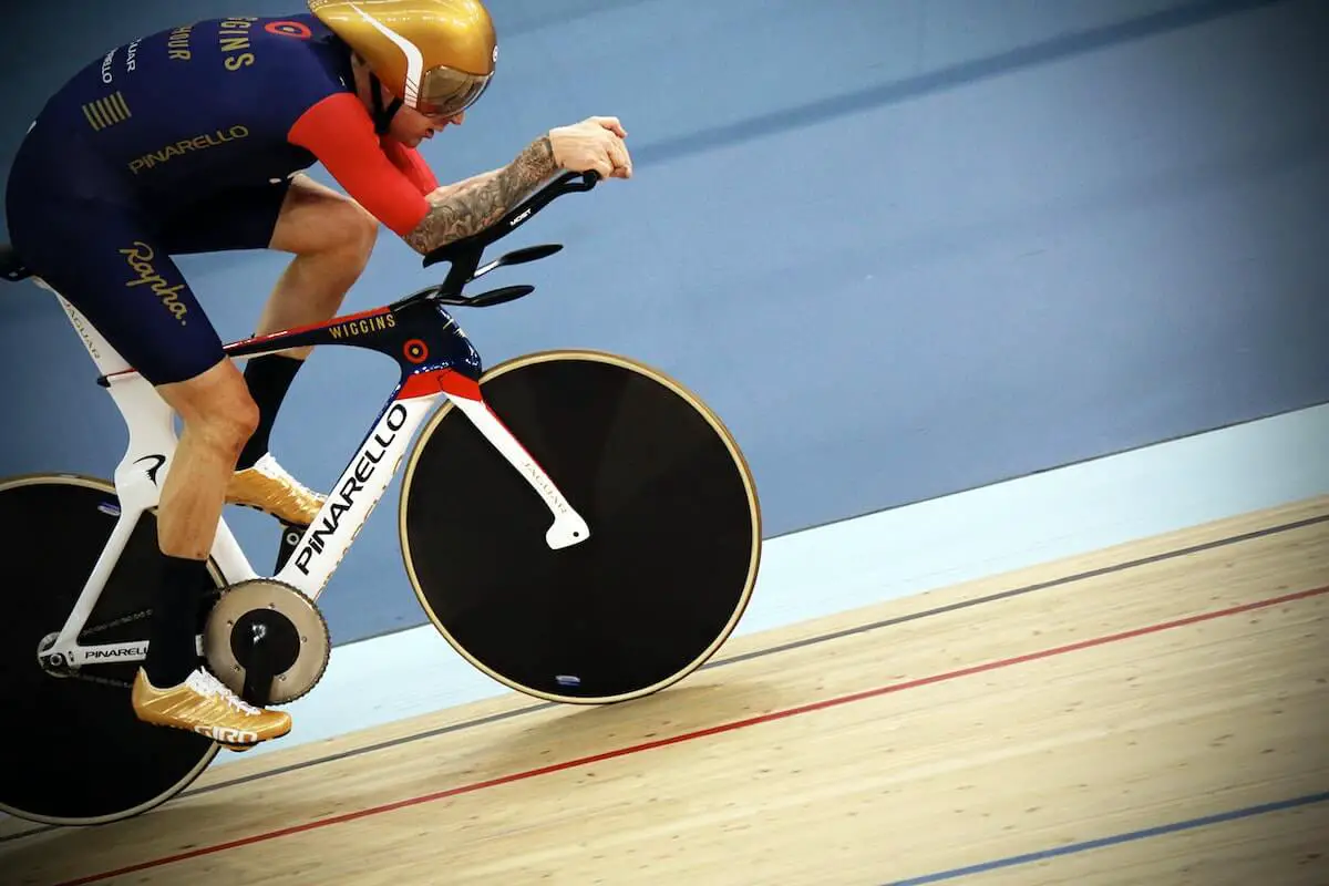 A cyclist at an indoor velodrome track riding a track bike.
