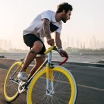 Image of a man riding fixed gear bike with a sunset backdrop.