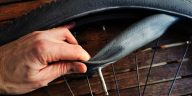Man replacing inner tube with a presta valve on a black bike tire. Source: Adobe stock.