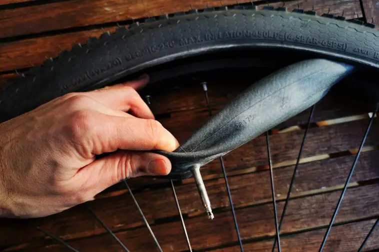 Man replacing inner tube with a presta valve on a black bike tire. Source: Adobe stock.