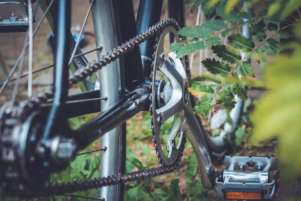 Image of a black single speed bike drive train and chain on grass.