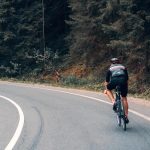 Image of a road cyclist climbing a hill near the forest. Source: Viktor Bystrov, Unsplash