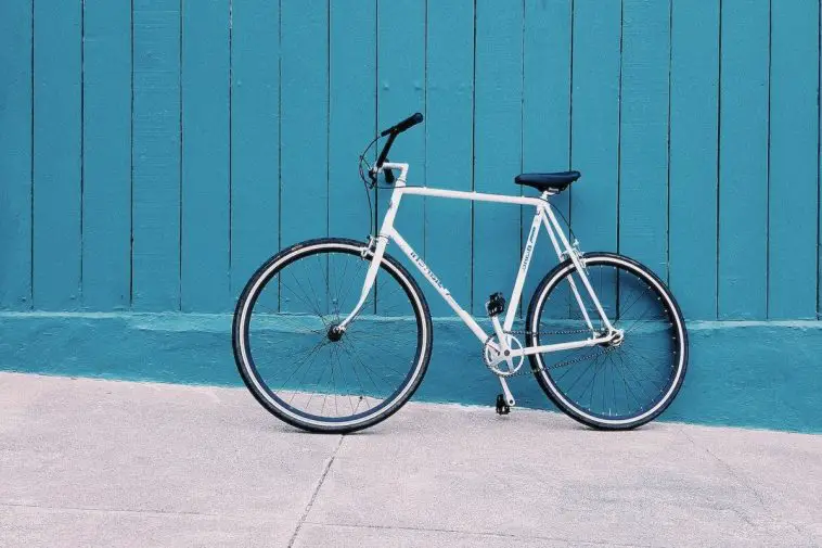 Image of white bike leaning on a blue wall. Source: Carl Nenzen Loven, Unsplash