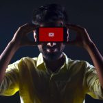 Man watching YouTube holding a phone to his head. Source: Rachit Tank, Unsplash