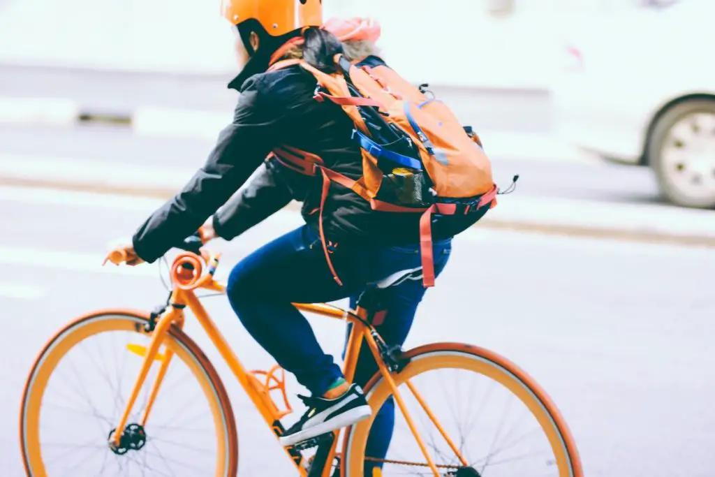 Image of commuter commuting on an orange fixed gear bike.