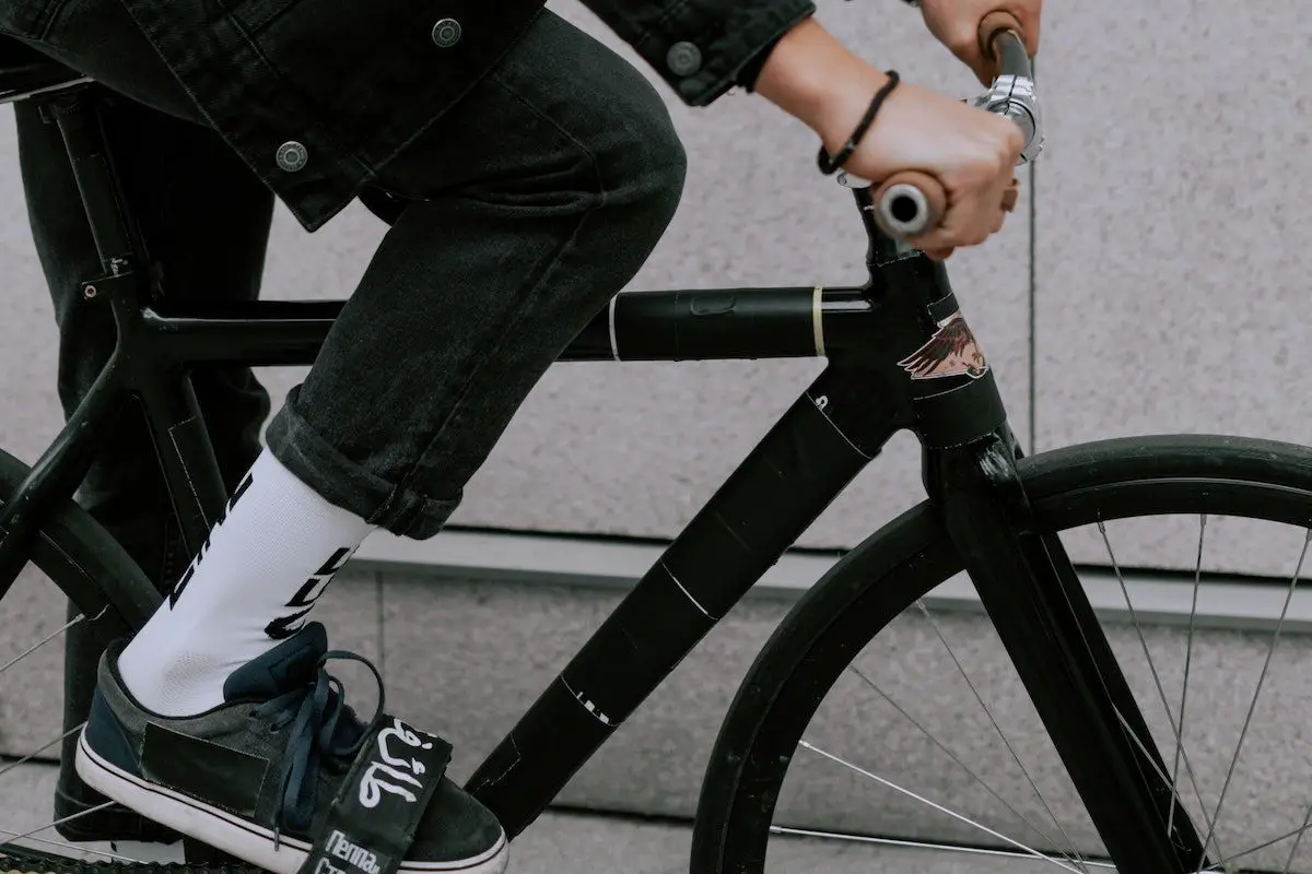 Young man riding a black fixed gear bike with pedal straps. Source: cottonbro, pexels