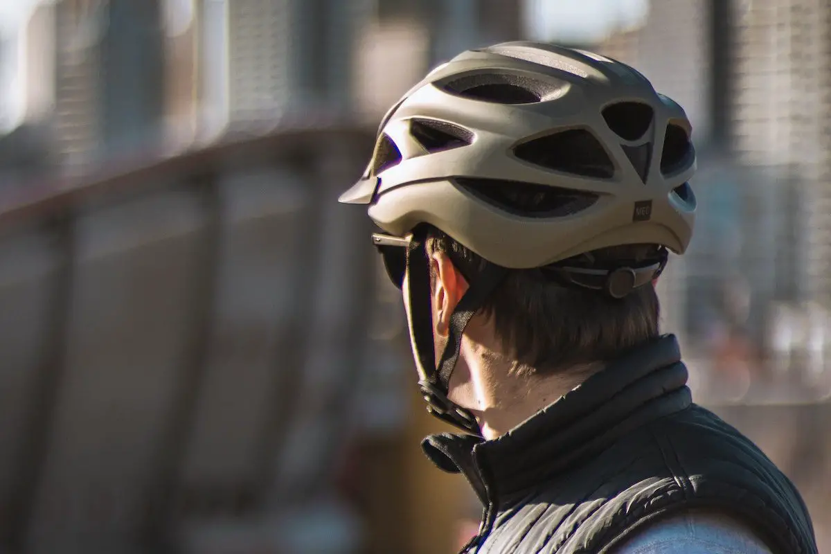 Image of a cyclist looking at the city skyline into the city wearing a bike helmet. Source: igor kyryliuk, unsplash