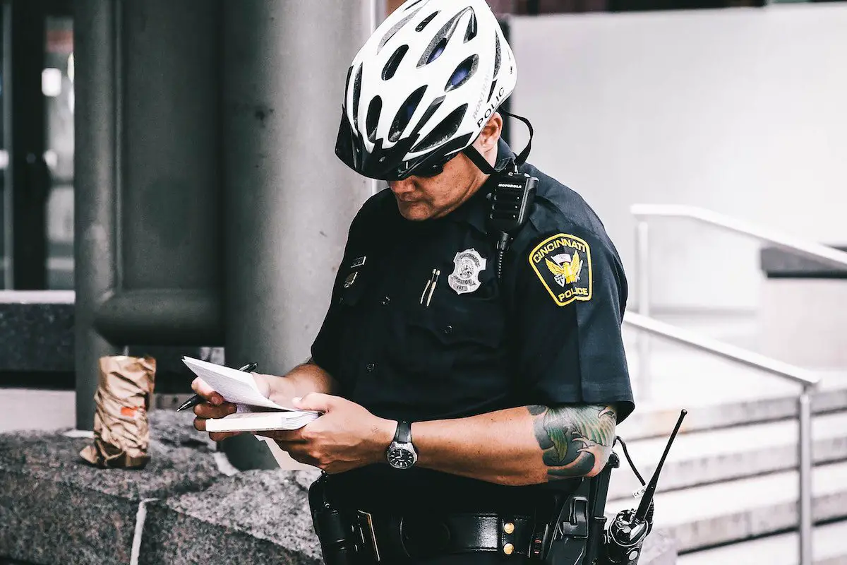 Image of a police officer wearing a cycling helmet writing a citation. Source: jordan, unsplash