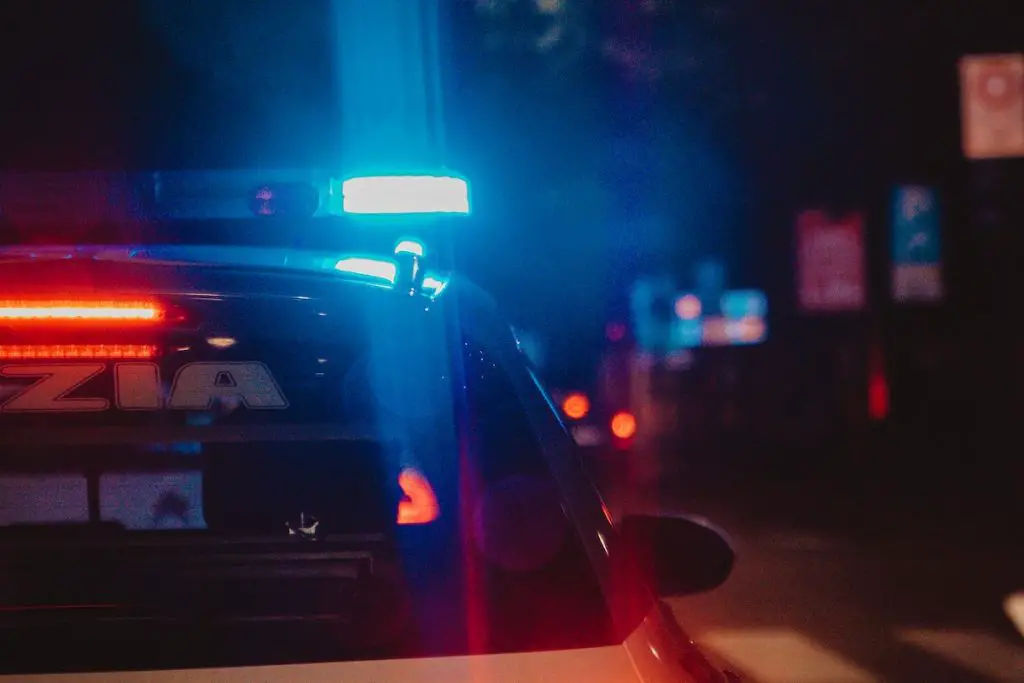 Image of a police vehicle at night with its lights on. Source: andrea ferrario, unsplash