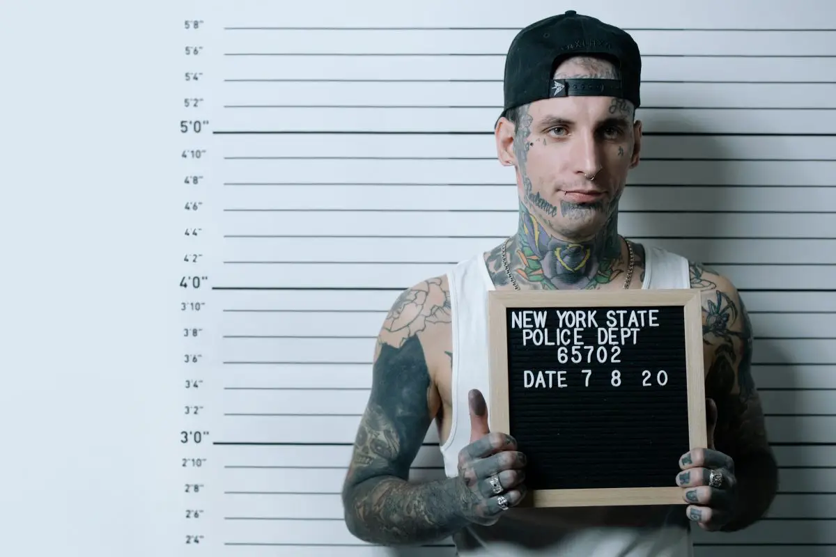 Man with many tattoos taking a mug shot at a police station. Source: cottonbro, pexels