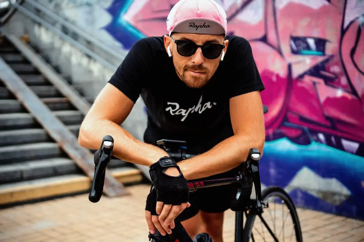 Many with a pink cycling cap, apple airpods, and sunglasses with a high performance bike. Source: unsplash