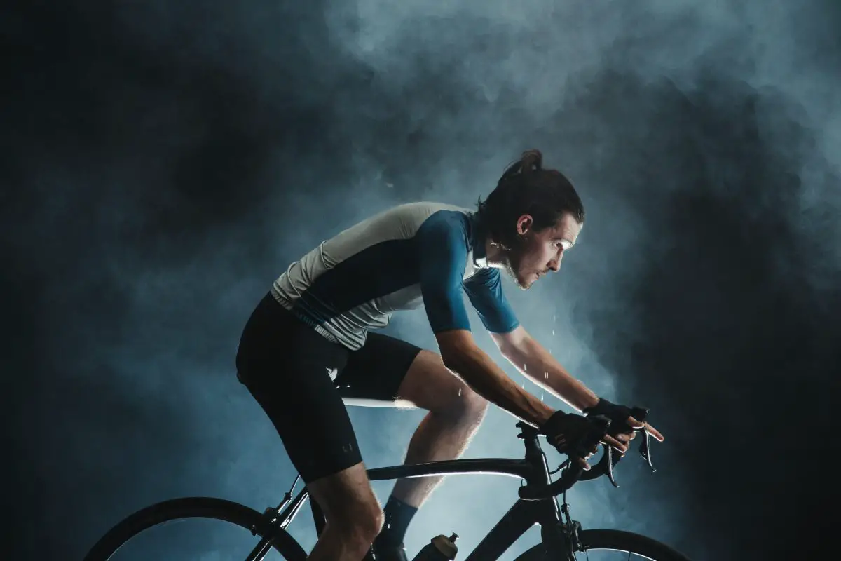 Image of a man cycling wearing cycling short and gear with a grayish backdrop. Source: munbaik cycling clothing unsplash