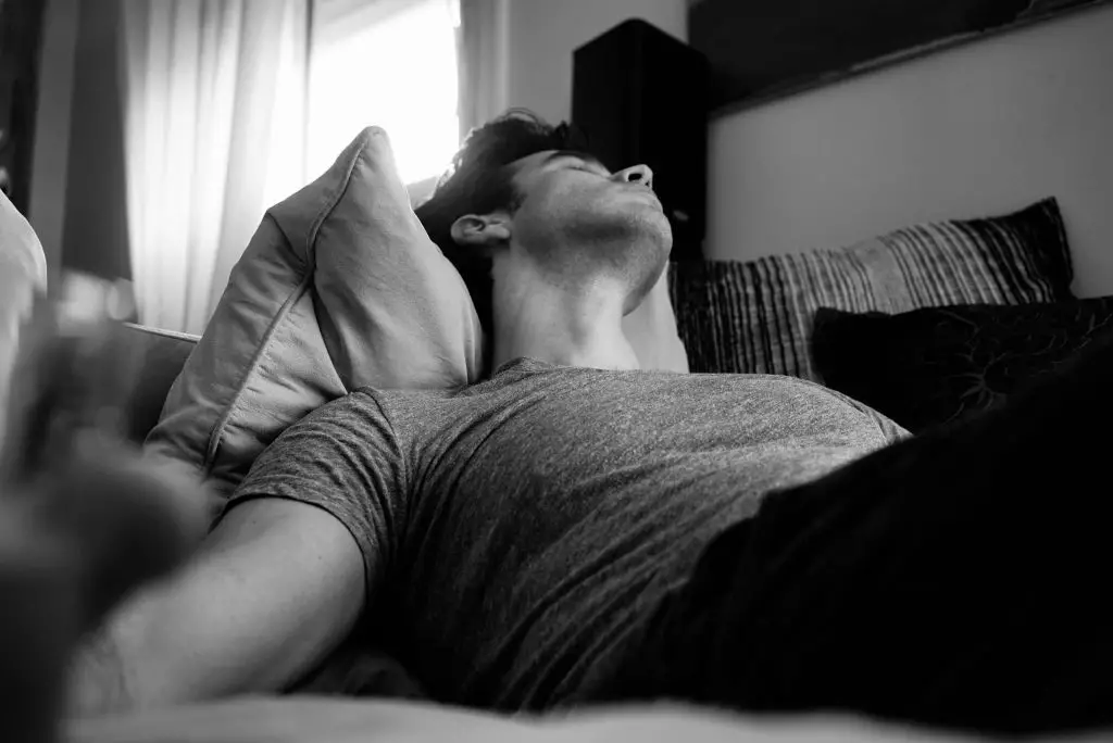 Balck and white image of a man sleeping on a sofa. Source: adi goldstein, unsplash