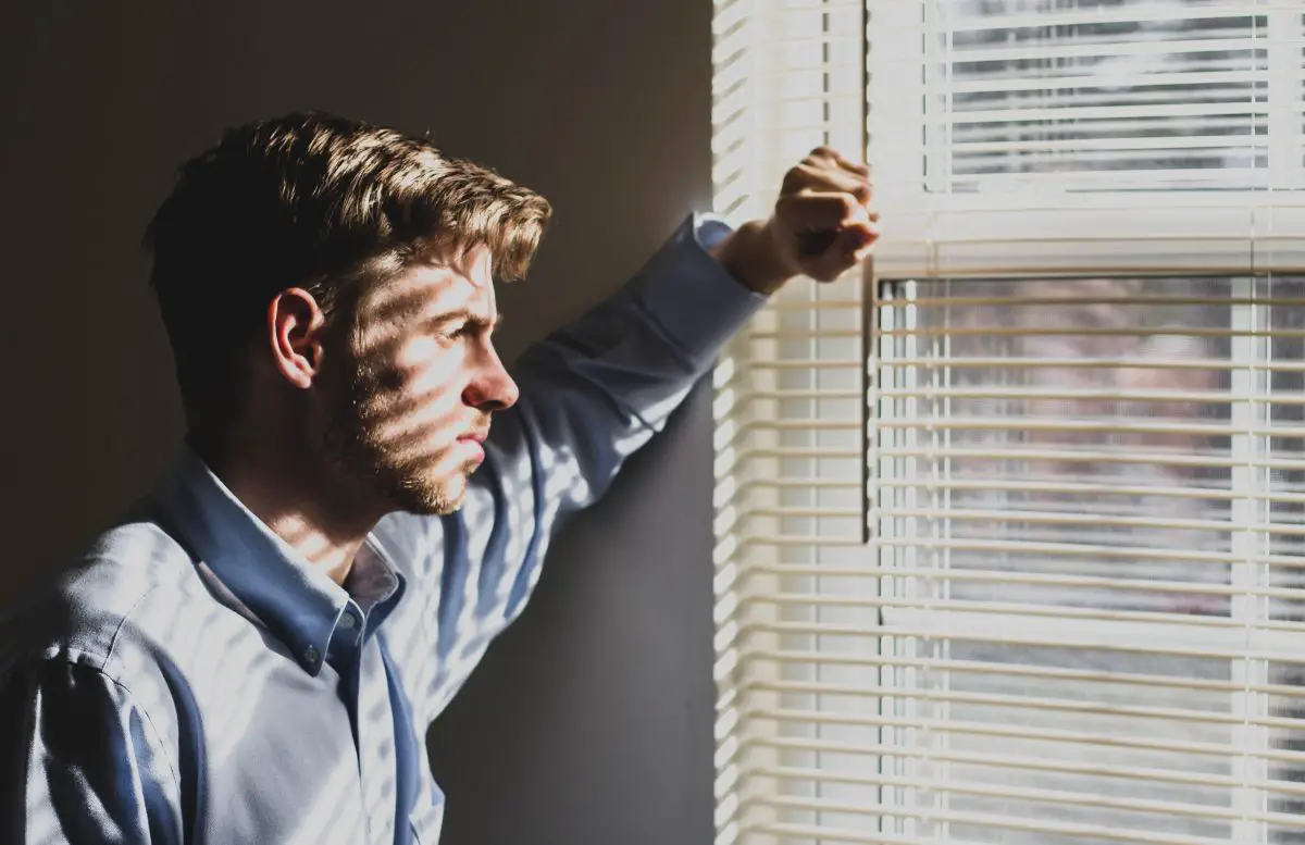 Image of a depressed man staring out the window. Source: ethan sykes, unsplash
