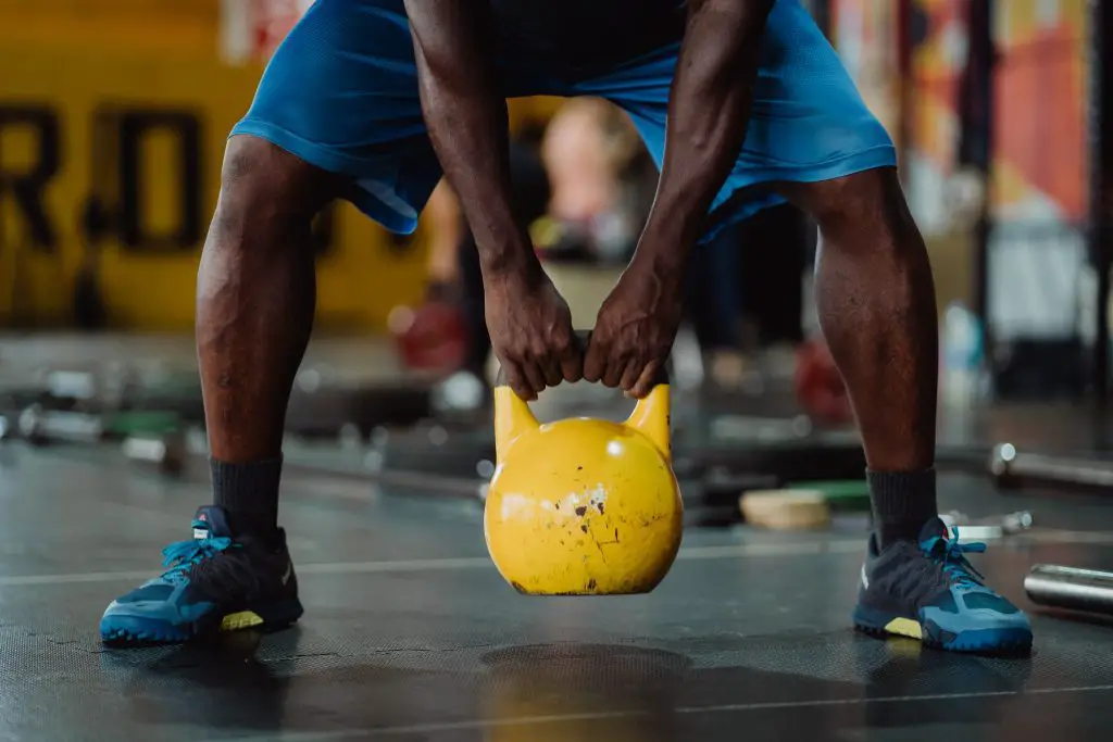 Image of a man holding a kettlebell. Source: ketut subiyanto, pexels