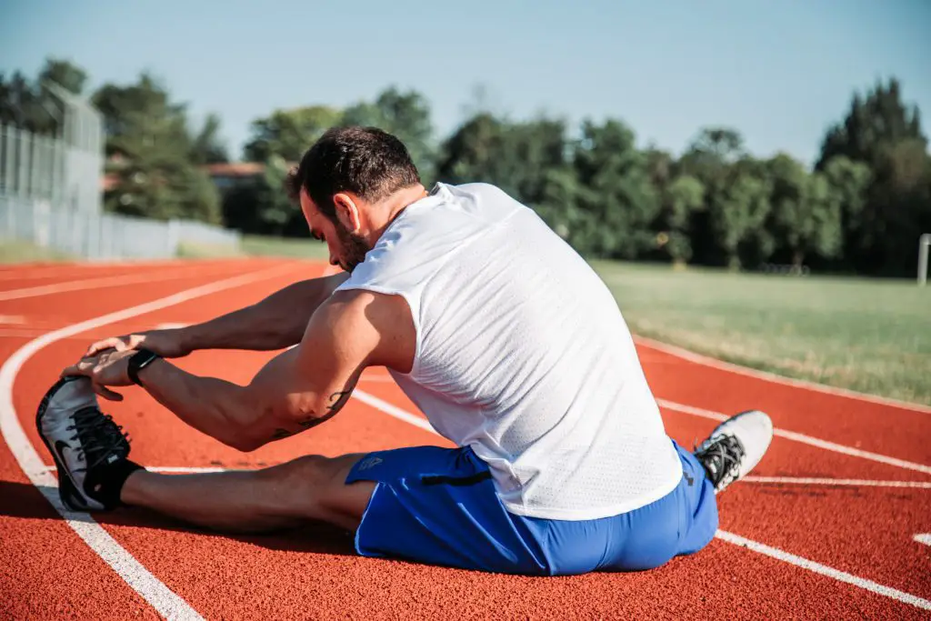 Image of an athlete stretching his hamstring. Source: alora griffiths, unsplash
