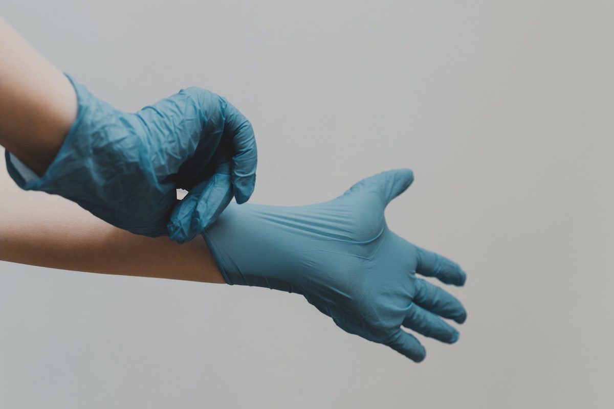 Image of doctor putting on surgical gloves. Source: clay banks, unsplash
