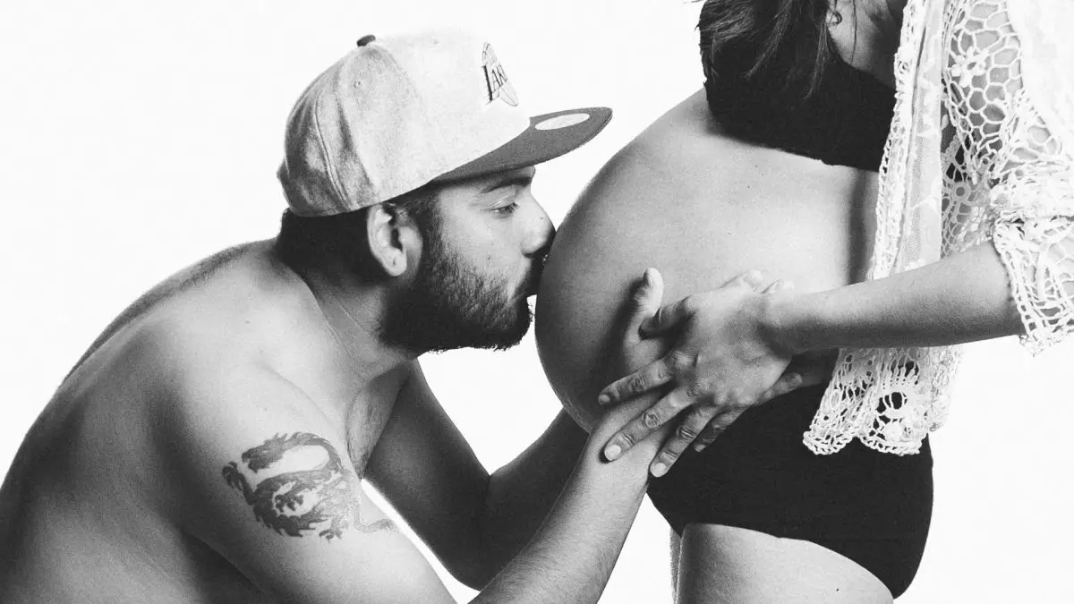 Image of man with hat kissing pregnant woman s belly. Source: pexels