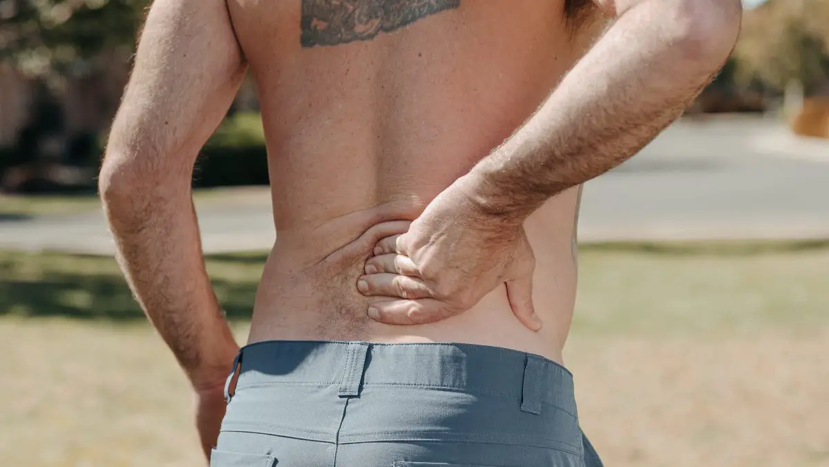 Image of man without a shirt holding his lower back in pain. Source: kindel media, pexels