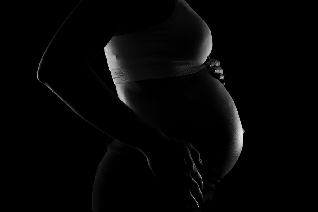 Image of a pregnant woman in the dark. Source: joao paulo de souza oliveira pexels