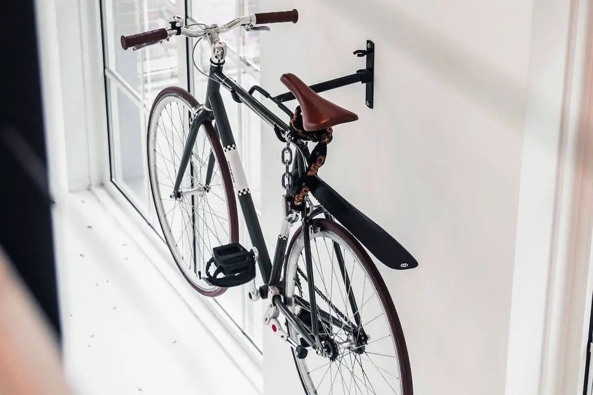 Image of a green fixed gear bike hanging in an apartment with white wall.
