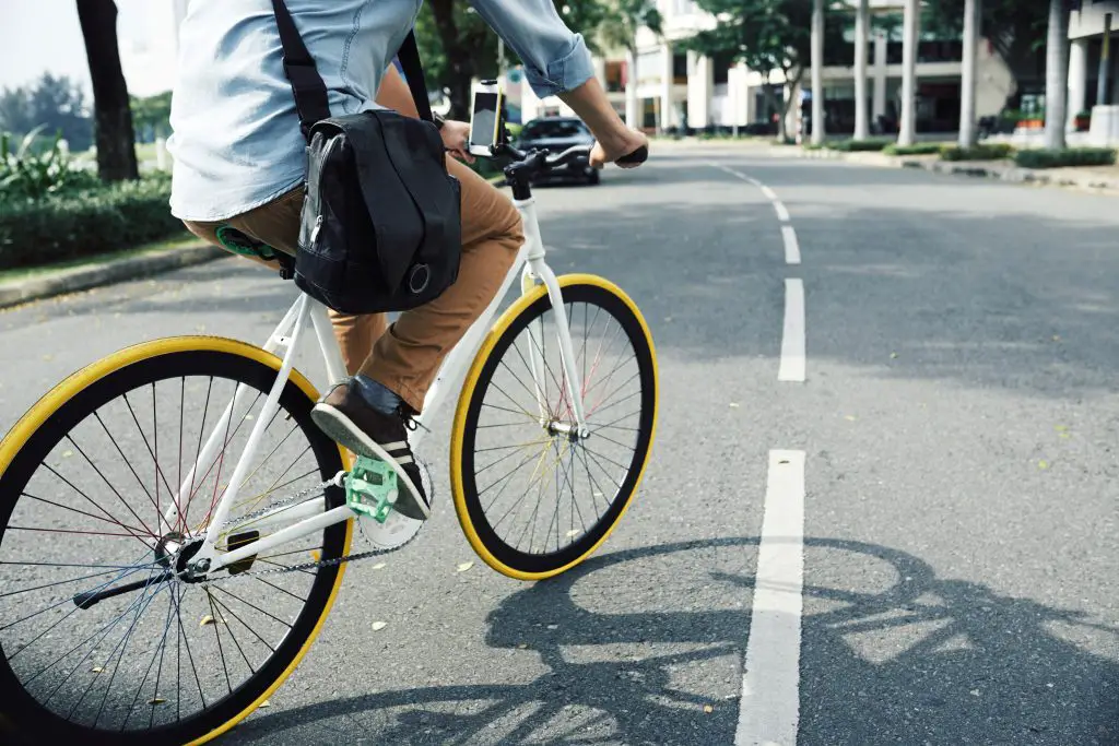 Man riding a white fixed gear or single speed bike with a messenger bag. Source: adobe stock