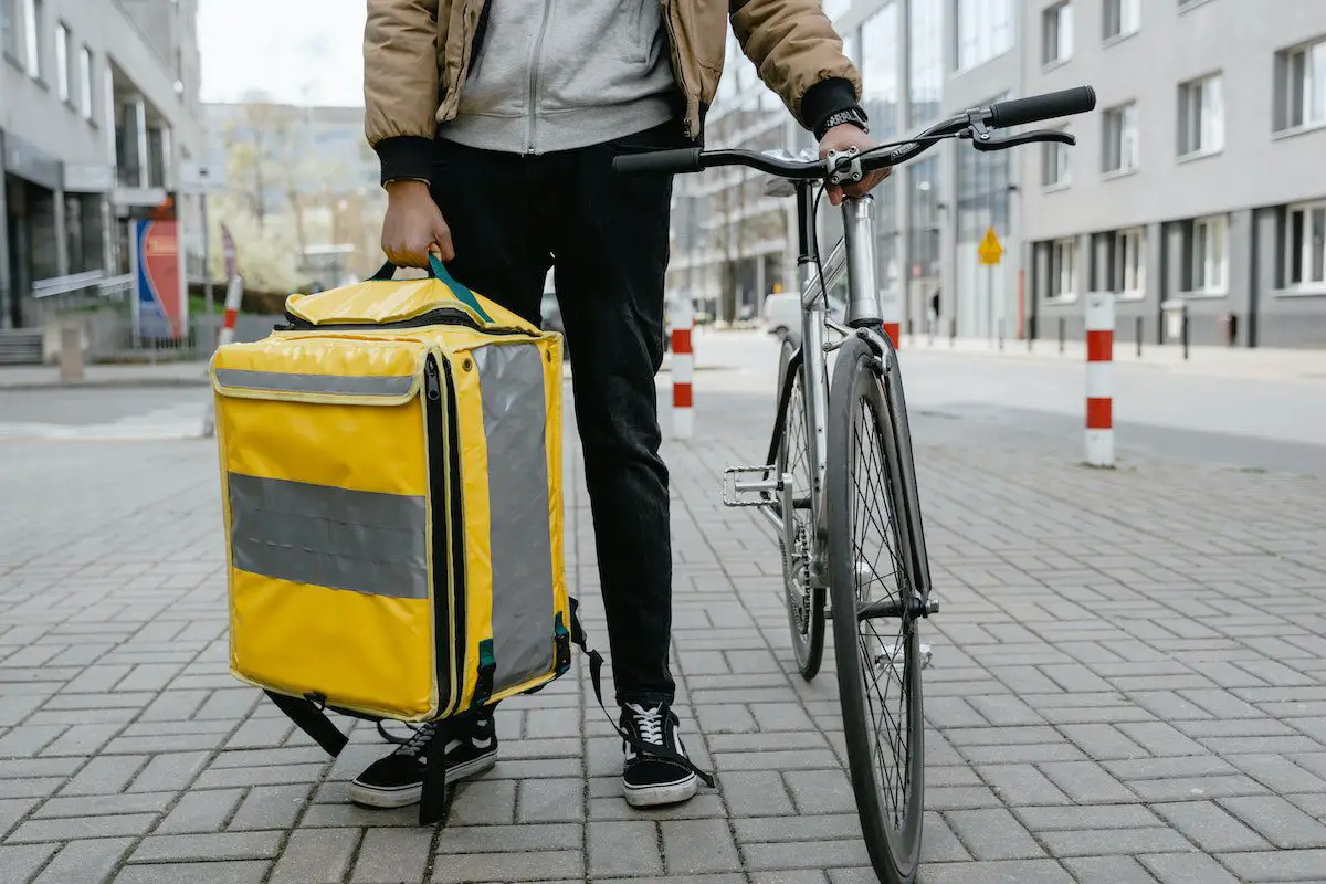 Man with yellow bike messenger bag holding a fixed gear bicycle. Source: mart production, pexels