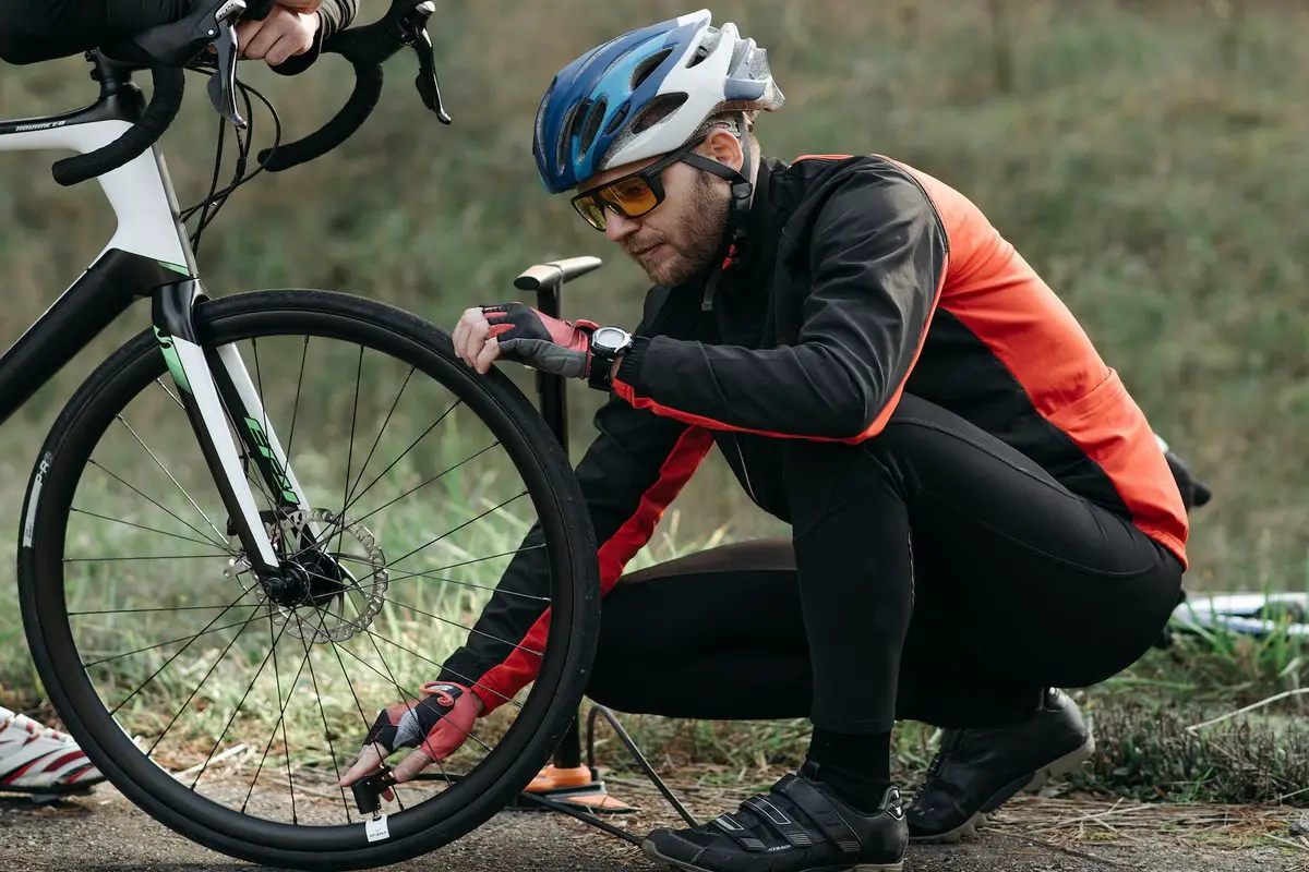 Image of a cyclist pumping air into a bike tire. Source: pexels