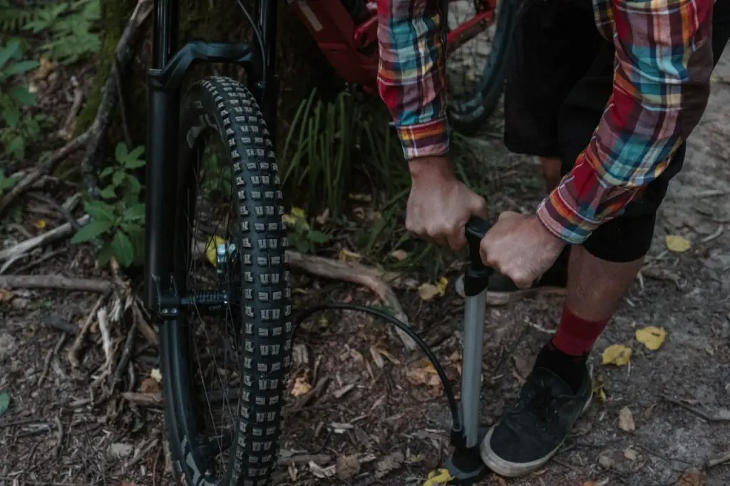 Image of a man pumping air into a bike tire source pexels