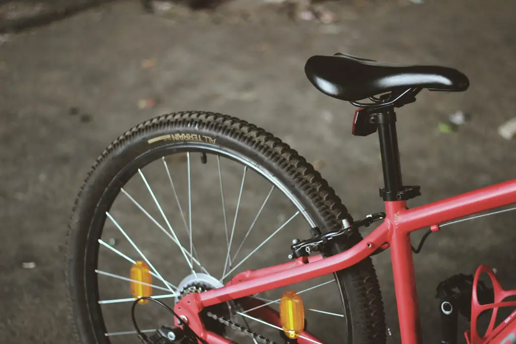 Close-up of a bicycle wheel in red frame. Source: unsplash