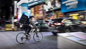 A bike messenger in the middle of a busy street. Source: Unsplash