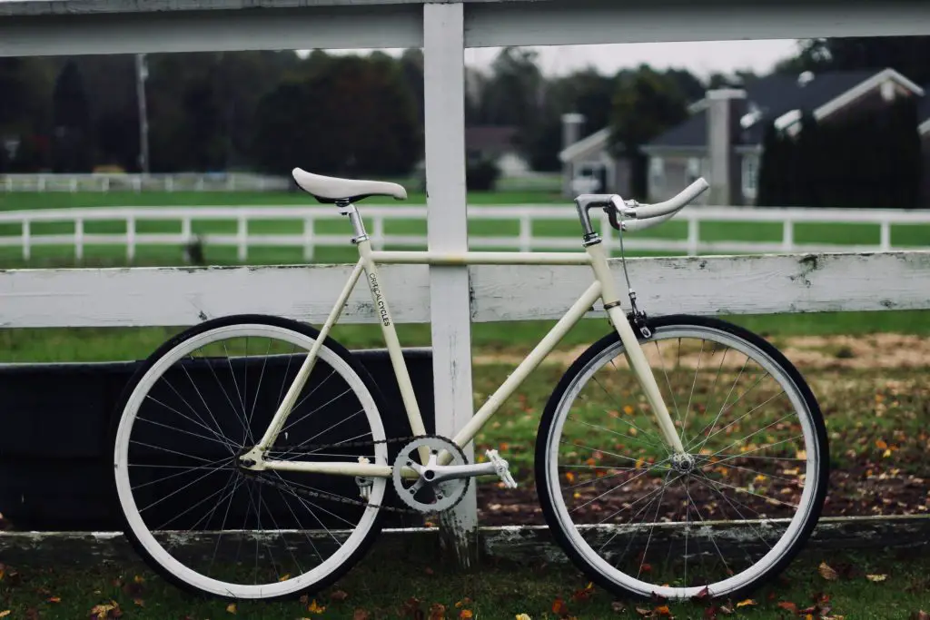 A white bicycle leaning on a fence. Source: unsplash