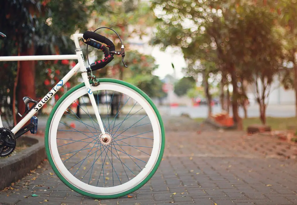 Closeup of a green bicyle wheel outdoors. Source: unsplash