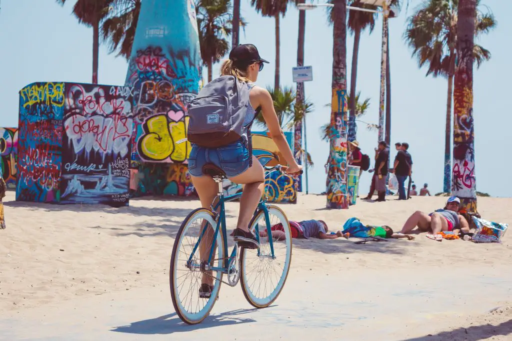 Woman riding a bicycle on a beach. Source: unsplash